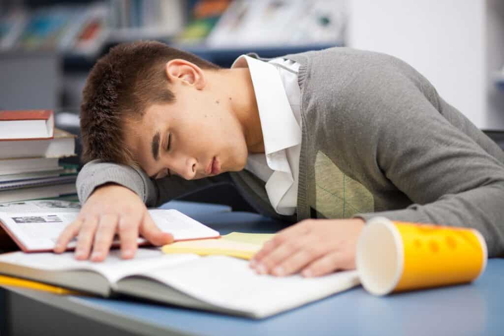 Estudante exausto dormindo sobre livros de estudo - técnicas de estudo erradas para concursos