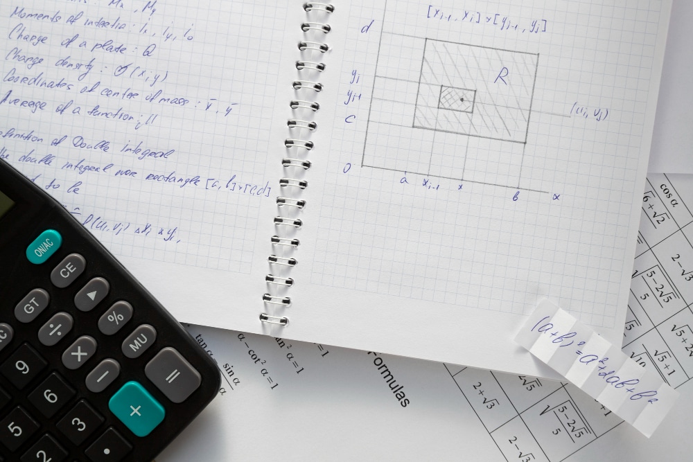 Caderno com anotações de matemática, calculadora e materiais de estudo para concurso da Petrobras sobre mesa