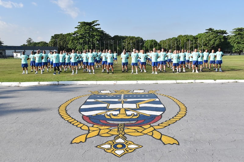 Candidatos do concurso SMV 2026 em formação durante treino físico na Marinha do Brasil com brasão oficial