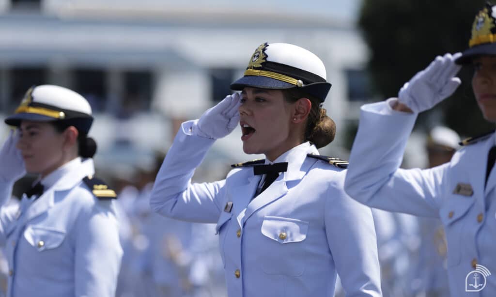 Oficial feminina da Marinha do Brasil em continência durante cerimônia militar vestindo uniforme branco de gala e quepe