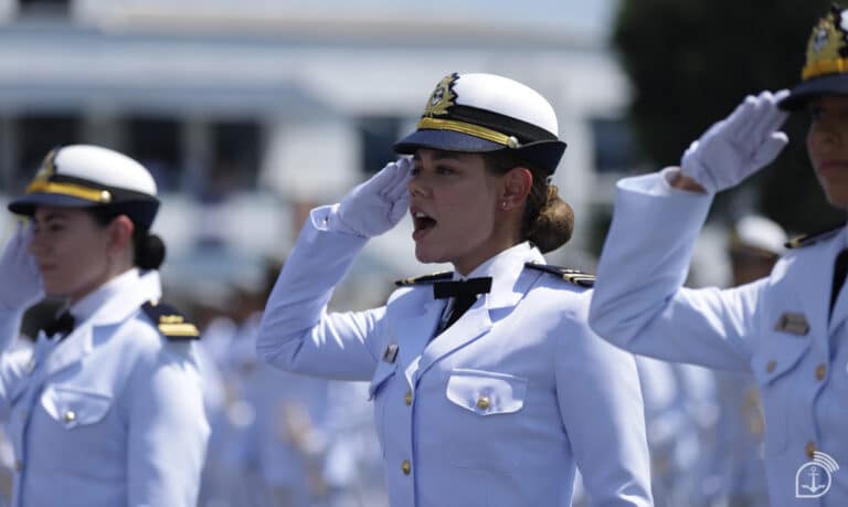 Oficial feminina da Marinha do Brasil em continência durante cerimônia militar vestindo uniforme branco de gala e quepe