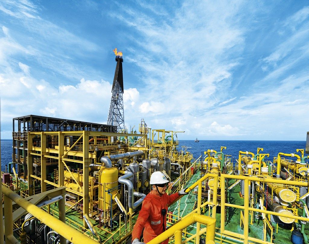 Técnico da Petrobras com uniforme laranja e capacete branco em plataforma offshore durante o curso de formação