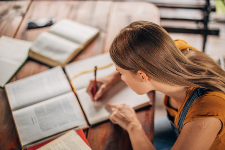 Estudar para o Banco do Brasil do zero com mulher concentrada lendo livros e fazendo anotações