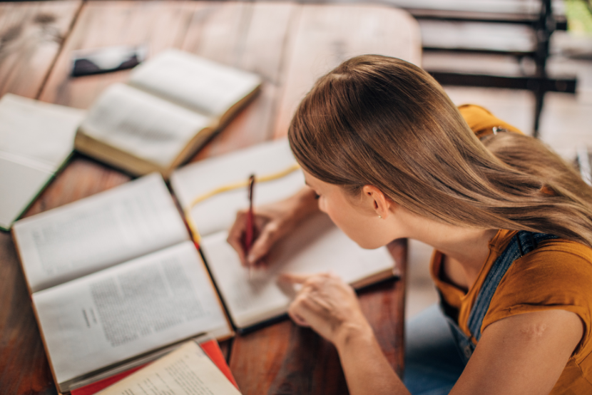 Estudar para o Banco do Brasil do zero com mulher concentrada lendo livros e fazendo anotações
