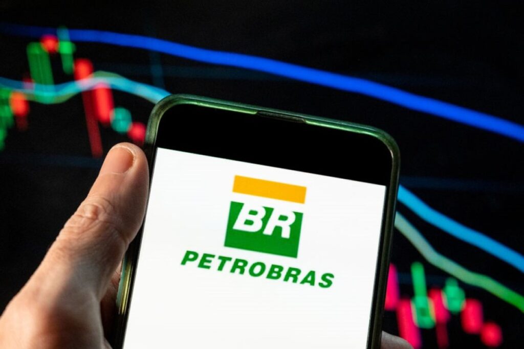 Logo da Petrobras em tela de celular com gráfico financeiro ao fundo