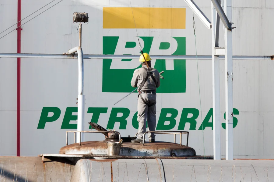 Operador da Petrobras trabalhando em tanque industrial com logo BR ao fundo
